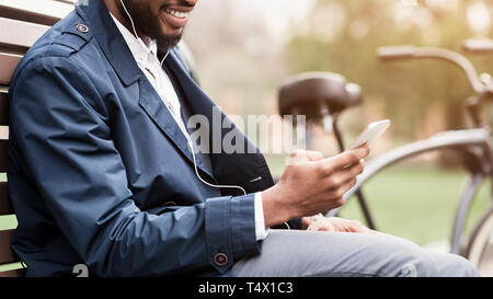 L'homme à d'écouteurs avec pause à l'extérieur ayant smartphone Banque D'Images