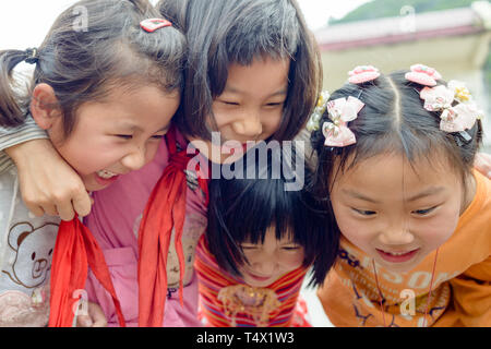 Quatre jeunes filles de l'école dans le groupe hug, rire et crier. Guangxi, région du sud de la Chine centrale. Banque D'Images