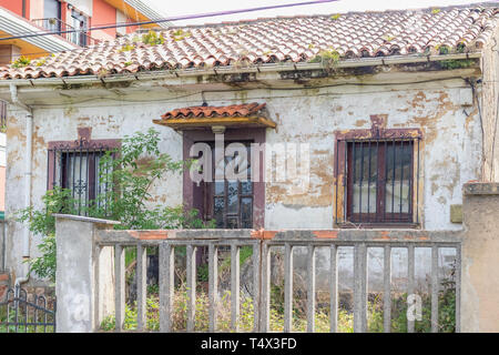 Ancienne maison envahie derrière une clôture délabrée. La notion de pauvreté et de solitude Banque D'Images