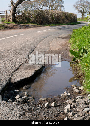 Dommages à la surface non réparés tarmac sur une route rurale Banque D'Images