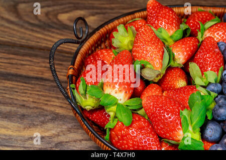 Frais sain mûrs fraises sucrées dans panier sur fond de bois Banque D'Images