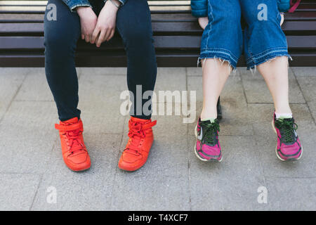 Homme et femme jambes dans des chaussures de sport sont assis sur un banc Banque D'Images