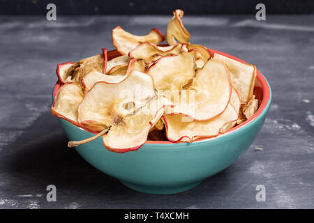 Close-up copeaux de pomme dans un bol turquoise sur fond gris foncé. Banque D'Images