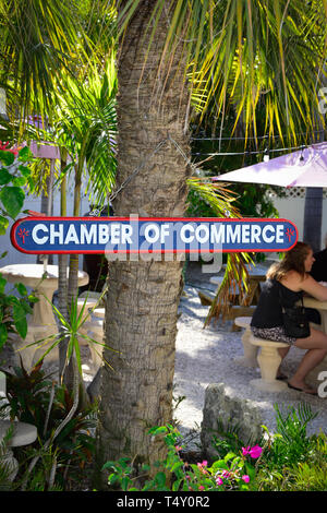 Les gens de l'extérieur du patio table avec parasol avec une chambre de commerce colorés sign à partir d'un palmier dans Boca Grande, FL, sur Gasparilla Island Banque D'Images