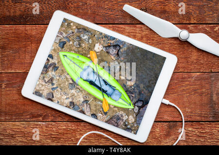 Kayak gonflable sur un rivage rocheux de la rivière de montagne, à l'examen d'une antenne de droit sur une tablette numérique Banque D'Images