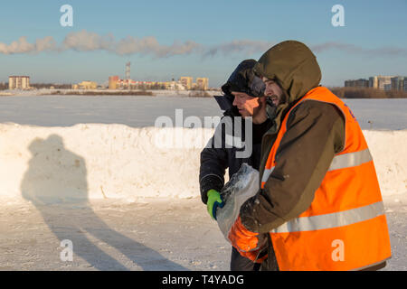 En hiver, les travailleurs portent des salopettes un bloc de glace à partir du trou dans leurs bras. Banque D'Images