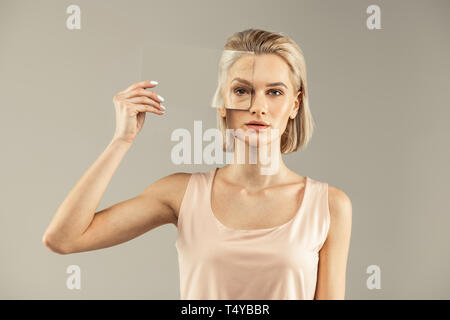 Jolie jeune femme en mettant un miroir pour l'oeil Banque D'Images