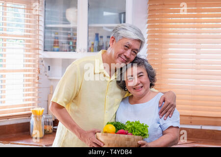 Bonheur Portrait asian senior couple en cuisine avec un bol de salade fraîche et à la caméra au vieillissement,à la maison conept. Banque D'Images
