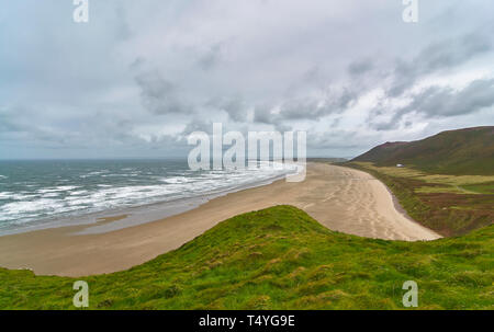 Le martèlement des vagues plage de Rhossili Bay sur la péninsule de Gower de galles, sur une journée venteuse étés gris en août. Le sud du Pays de Galles. Banque D'Images