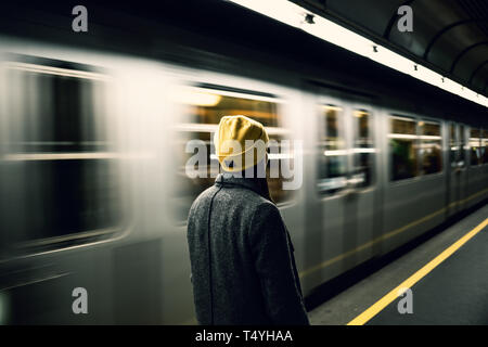 Jeune femme attend à la station de métro tandis que le train arrrives. Transports et déplacements concept. Banque D'Images