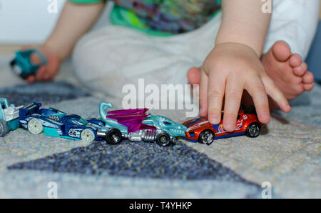 La queue de l'enfant jouets sur le plancher à la maison. Kid alignant voitures de jouet sur le plancher. Banque D'Images