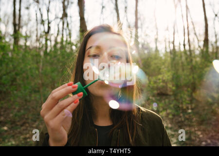 Jeune femme soufflant des bulles de savon dans les bois. La liberté, le mode de vie et la mise en réseau concept. Regarder film analogique vintage coloré. Banque D'Images