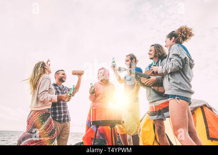 Groupe d'amis ayant un barbecue boire des bières tout en camping sur la plage - Happy people enjoying barbecue camp à jouer de la guitare et écouter de la musique Banque D'Images