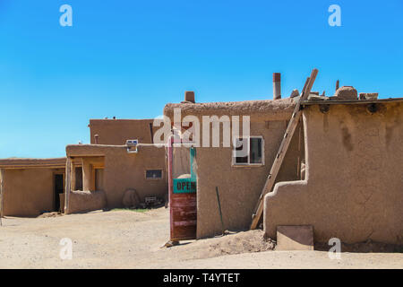 Vue latérale des bâtiments dans une boue adobe pueblo dans le sud-ouest de la France, avec des magasins avec des portes ouvertes pour d'artisanat local et les aliments pour les touristes Banque D'Images