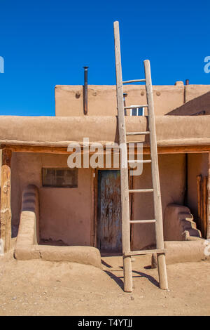 Deuxième histoire de l'échelle conduisant à des appartements sur adobe boue traditionnel pueblo avec porche et porte en bois old grunge dans sud-ouest américain Banque D'Images