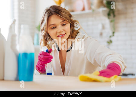 Nettoyer les surfaces. Belle blonde woman looking at le compteur pendant le nettoyage de surface il Banque D'Images