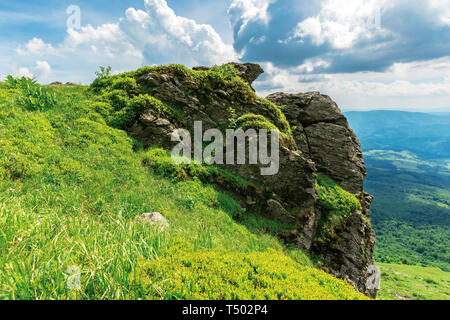 Été la nature paysages de montagnes. énorme formation rocheuse au bord d'une pente herbeuse. vue dans la vallée éloignée. beau temps avec ciel nuageux. Banque D'Images