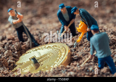 Figurines mineur macro creusant pour découvrir grand bitcoin brillant Banque D'Images