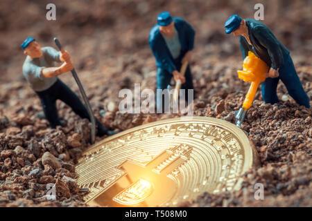 Figurines mineur macro creusant pour découvrir grand bitcoin brillant Banque D'Images