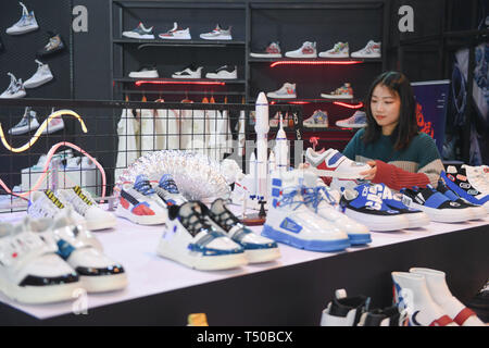 Jinjiang, province de Fujian en Chine. Apr 19, 2019. Un commerçant se penche sur des souliers faits via les commandes en ligne au cours de la 21e Chaussures Jinjiang & la 4e exposition internationale de l'industrie des sports à Jinjiang, dans le sud-est de la province de Fujian en Chine, le 19 avril 2019. Ouverture d'ici le vendredi, l'événement a 2 200 cabines pouvant accueillir plus de 500 exposants à l'échelle mondiale. Credit : Chanson Weiwei/Xinhua/Alamy Live News Banque D'Images