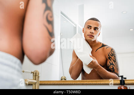 Jeune homme d'essuyer le visage avec une serviette après le rasage Banque D'Images