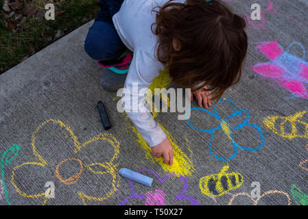 Une jeune fille dessin avec craies de trottoir sur le trottoir en été. Banque D'Images