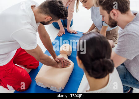 Formateur performing cpr on dummy au cours de formation en premiers soins avec groupe de personnes Banque D'Images