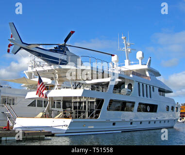 Un hélicoptère personnel garanti sur un pont supérieur est un imposant l'agrément qui attend l'utilisation par le riche propriétaire de ce yacht de luxe à quai dans le port de Newport dans la ville balnéaire de Newport Beach, Californie, USA. Banque D'Images