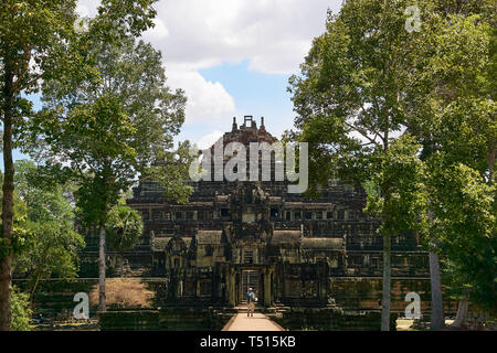 Un homme adulte promenades touristiques le long de la chaussée menant à l'ancien temple Baphuon grès à midi dans le parc archéologique d'Angkor, au Cambodge. Banque D'Images