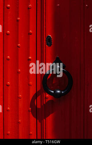 La porte rouge avec poignée forgée big black. Banque D'Images