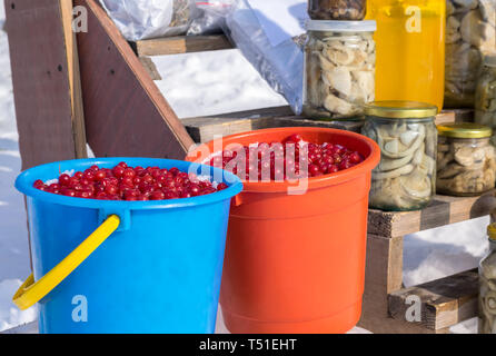 Marché rural. Vente d'espaces d'hiver sur la rue libre en hiver dans la neige. Les baies du viburnum, mountain ash dans des seaux. Salé, mariné mushr Banque D'Images