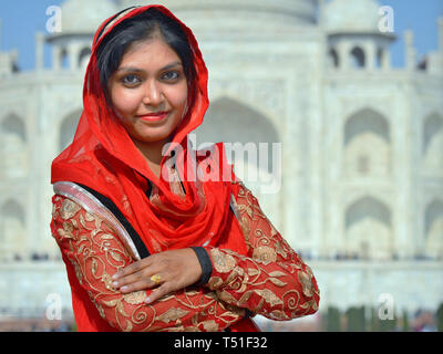 Belle jeune femme indienne en rouge pose devant le Taj Mahal. Banque D'Images