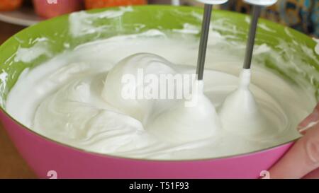 Mélangeur de cuisine bat la crème pâtissière crème fouetter tourne rapidement. Robot de cuisine battre les oeufs blancs en blanc une mousse épaisse. Machine en cuisine Banque D'Images