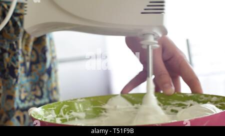Mélangeur de cuisine bat la crème pâtissière crème fouetter tourne rapidement. Robot de cuisine battre les oeufs blancs en blanc une mousse épaisse. Machine en cuisine Banque D'Images