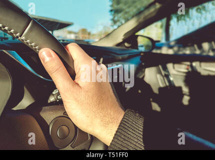 Apprentissage conduite main droite sur le volant à l'intérieur d'une voiture avec la circulation à gauche de la lumière du matin Banque D'Images
