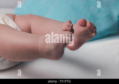 Jambes dodues mignonnes d'un bébé nouveau-né sur un fond de bleu et blanc à carreaux Banque D'Images