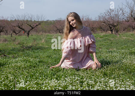 Belle blonde femme perçoit la couleur du printemps dans le jardin Banque D'Images