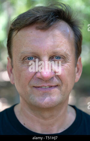 Portrait d'un homme d'âge moyen qui repose sur un fond de feuilles vertes en journée ensoleillée sur la nature, Close up Banque D'Images