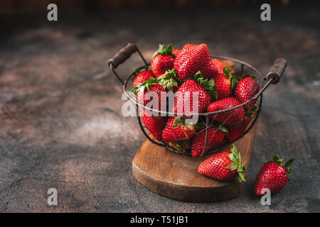 Fraises Juteuses frais dans le panier avec des feuilles sur fond rustique Banque D'Images