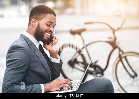 Toujours en contact. Happy manager working on laptop, avoir briser l'extérieur Banque D'Images