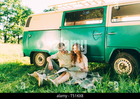 Jeune garçon et fille à l'extérieur l'étude d'un site s'appuyant sur un bus vert vintage Banque D'Images