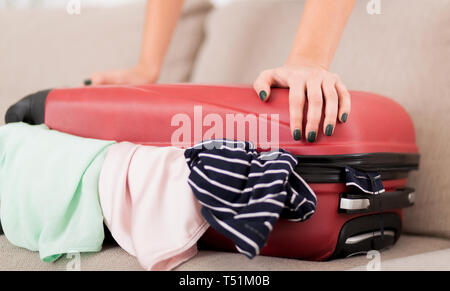 Valise d'emballage. Femme essayant de fermer full suitcase Banque D'Images