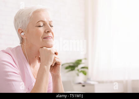 Musique Senior woman at home with closed eyes Banque D'Images