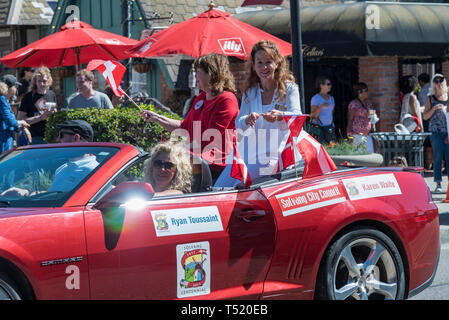 Voiture décapotable rouge avec le conseil municipal, les femmes en retour, les spectateurs au-delà dans le défilé. Banque D'Images