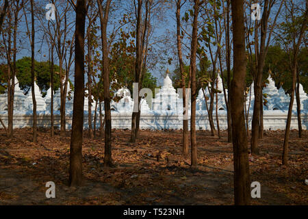 À travers les arbres à l'extérieur du complexe, quelques-unes des plus de 700 stupas qui contiennent chacun une dalle de la plus grande réserve au monde. À la pagode Kuthodaw Banque D'Images