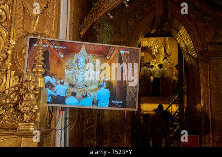 Les gens à l'autel principal au temple le plus vénéré à Mandalay, Myanmar , le Temple du Bouddha Mahamuni. Les moniteurs vidéo aider les gens à voir la feuille d'or être Banque D'Images