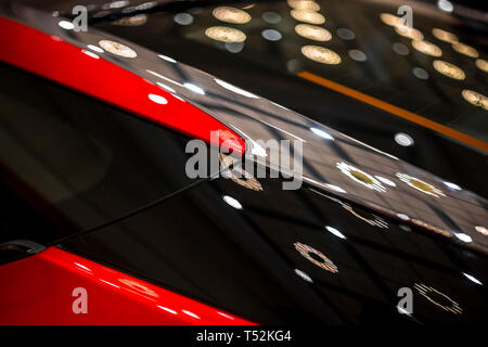 Fragment d'une voiture de luxe deux couleurs trimestre cutter peint en noir avec des accents de rouge et de réflexion de l'éclairage des lampes sur une surface brillante, Brillante voiture Banque D'Images