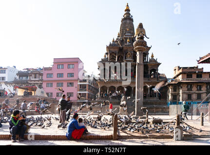 Katmandou, Népal - 28 décembre 2015 : les personnes observant les pigeons dans la cour en face de l'Krishna Mandir à Patan Durbar Square. Banque D'Images