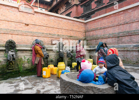 Katmandou, Népal - le 11 janvier 2016 : les femmes locales d'eau de remplissage à la pierre traditionnelle de pouvez touchez pour usage domestiques quotidiennes à Patan. Banque D'Images