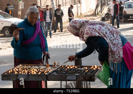 Katmandou, Népal - 11 novembre, 2017 : deux femmes lighting lampes à beurre après leur prière à Swoyambunath. Banque D'Images